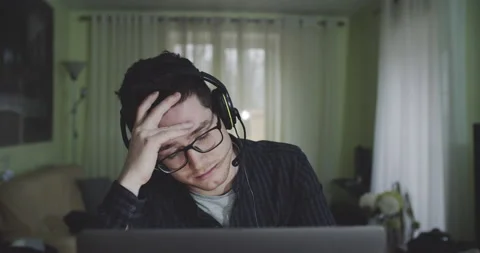 Portrait of young man working in front of computer at home, talking to a group Stock Footage 154284429