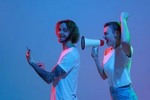 Portrait of young man working on tablet and woman shouting in megaphone isolated Stock Photos