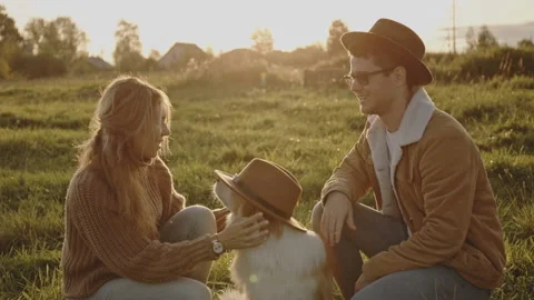 Portrait of young married couple of millennials on walk in field with dog or Stock Footage 144310104