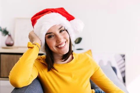 Portrait of young millennial female in Santa Claus hat smiling at camera Stock Photos