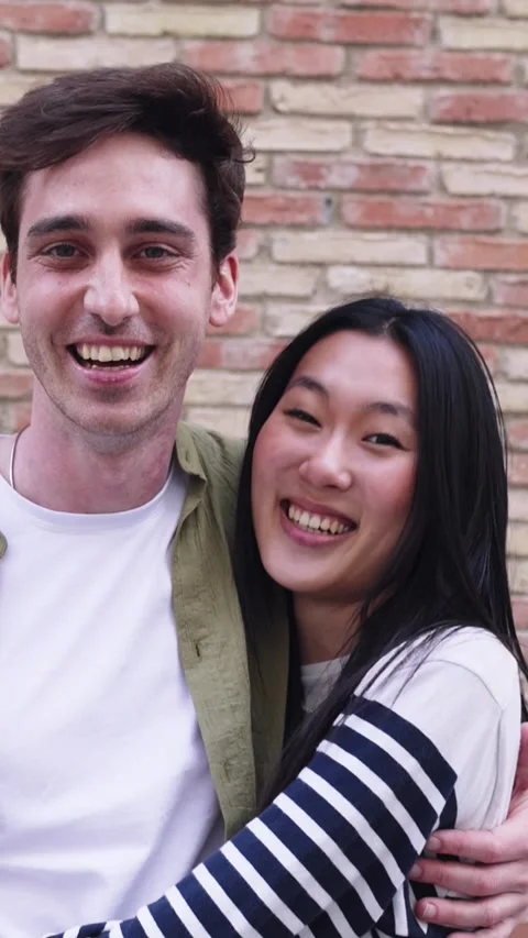 Portrait of young multiracial couple smiling at camera over wall background Stock Footage 282924226