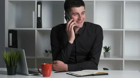 Portrait of a young office worker manager sitting at his desk and talking to Stock Footage 134577434