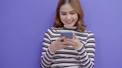 Portrait of young pretty woman is using smart phone over blue background 库存影片 157301549
