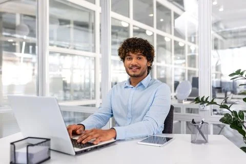 Portrait of young programmer inside office with laptop, indian man smiling and Stock Photos