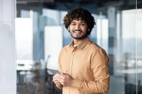 Portrait of young programmer with tablet computer inside office, hispanic man 스톡 사진