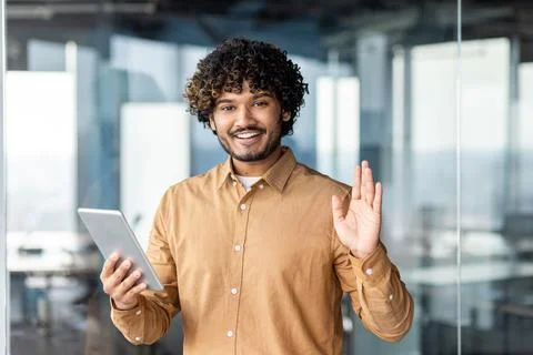 Portrait of young programmer with tablet computer inside office, hispanic man 写真素材