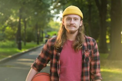 Portrait of a young red-haired guy in a yellow hat with a basketball Stock Photos