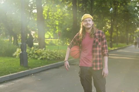 Portrait of a young red-haired guy in a yellow hat with a basketball Stock Photos