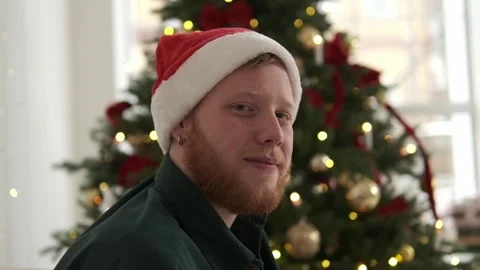 Portrait of a young red-haired man in a Santa hat. Stock Footage 294038931