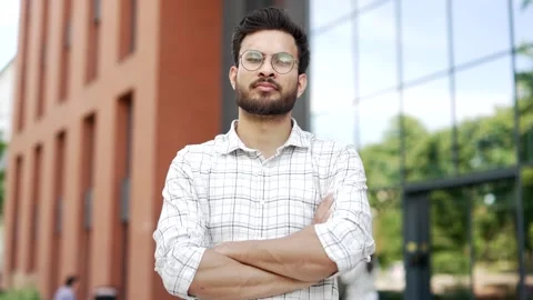 Portrait of a young serious man standing with crossed arms on the street near  Stock Footage 306302553