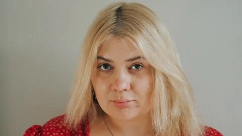 Portrait of young serious plus-size or overweight blonde woman looks at camera Video stock 242991653