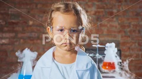Portrait of a young serious scientist child girl in a chemistry lab. Stock Photos