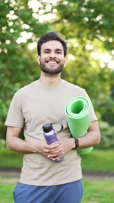 Portrait of young smiling athletic man standing outdoors in urban city park Stock Footage 306308870