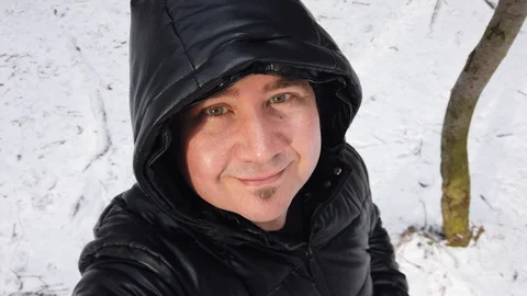 Portrait of young smiling man on the background of snow in the winter forest Video stock 123573167