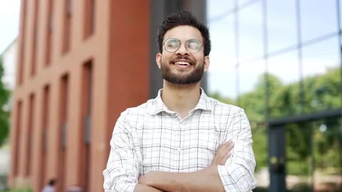 Portrait of a young smiling man standing with crossed arms on the street near  Stock Footage 306302586