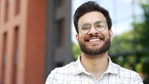 Portrait of a young smiling man standing on the street near an modern office  Stock Footage 306302812