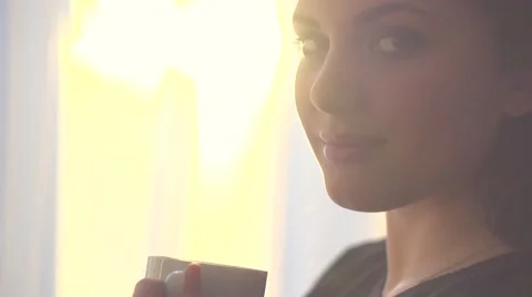 Portrait of young smiling woman looking out window and drinking coffee Video stock 50051353