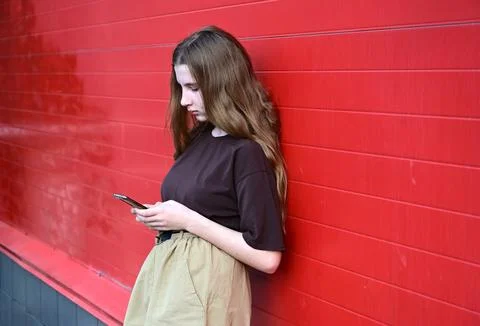 Portrait of a young student reading a message on a mobile phone, a stylish .. Stock Photos