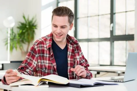 Portrait of a young student smiling while researching information Stock Photos