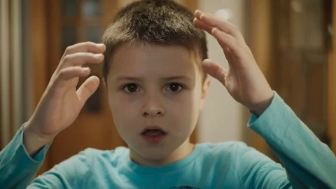 Portrait young surprised boy looking at camera touches the hands of the head Stock Footage 127168801