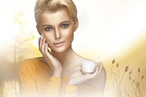 Portrait of young woman applying moisturizer cream on her clear face Stock Photos