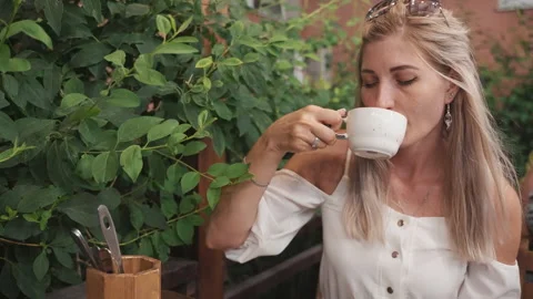 Portrait of a young woman drinking coffee in a restaurant in the evening Видео 205893553