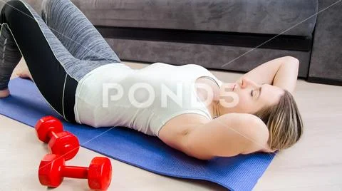 Portrait of young woman hardly breathing after doing sit-ups Stock Photos