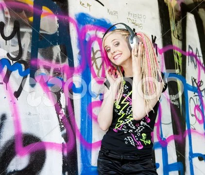 Portrait Of Young Woman With Headphones At Graffitti Wall