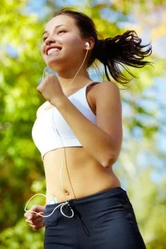 Portrait of a young woman jogging with a walkman Stock Photos