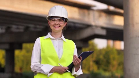 Portrait of a young woman, a master builder in a protective helmet, looking at Stock Footage 200790973