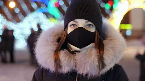 Portrait of young woman with a protective mask in a pandemic stands against the Stock Footage 166326830