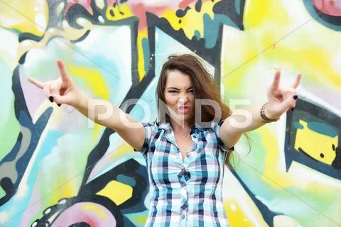 Portrait of young woman sitting at graffiti wall Stock Photos
