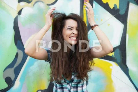 Portrait of young woman sitting at graffiti wall Stock Photos