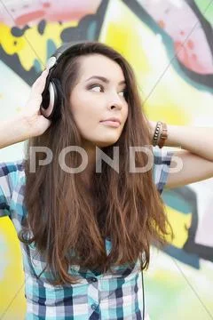 Portrait of young woman sitting at graffitti wall Stock Photos