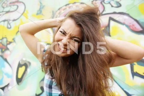 Portrait of young woman sitting at graffitti wall Stock Photos