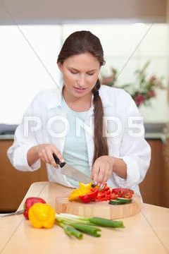 Portrait of a young woman slicing a pepper Stock Photos