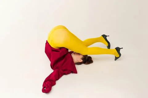 Portrait of young woman in yellow tights, red jacket and heels posing isolated Stock Photos
