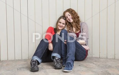 Portrait of young women leaning against planked wall, smiling Stock Photos