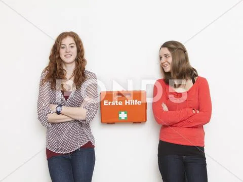 Portrait Of Young Women Leaning Against Wall With First Aid Kit, Smiling
