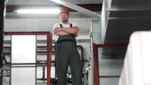 Portrait of a young worker in a uniform and a hard hat looking at the camera. Stock Footage 306815065