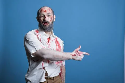 Portrait of zombie pointing with finger to empty copy space, studio background Stock Photos