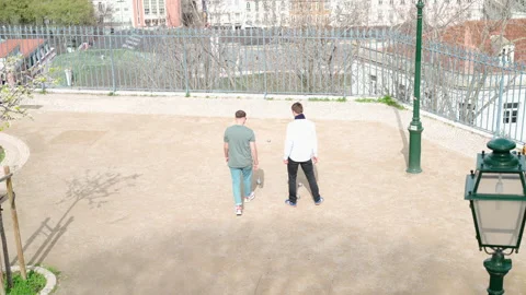 Portugal, Lisbon March 2022 Two man plating petanque at park in Lisbon. Leisure Stock Footage