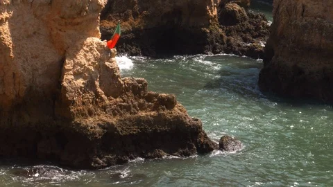 Portuguese flag in the wind at Ponta da Piedade bay consisting of Impressive Stock Footage 115907494