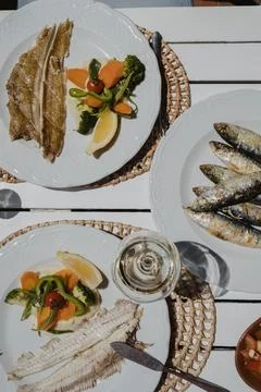 Portuguese seafood restaurant table, mixed plates and sardines with white wine. Stock Photos