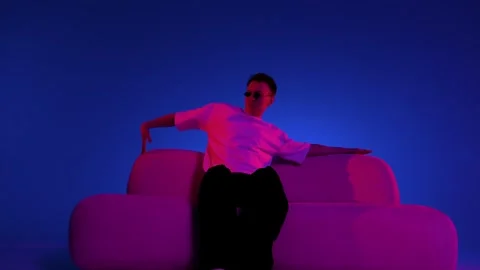 Posed sofa portrait with arms stretched and neon lighting Stock Footage 345601943