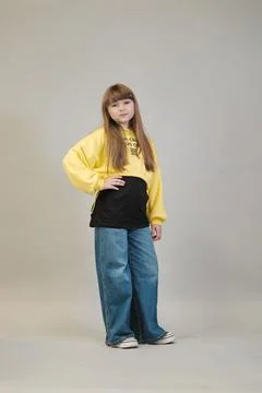 Posing with her hands on her hips, a girl in a black t-shirt and wide-leg jeans Stock Photos