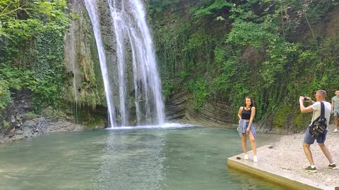Posing for a photo on the background of a waterfall Stock Footage 155577683
