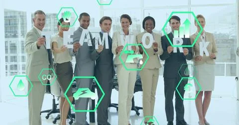 Posing team of eight wearing suits in office, holding TEAMWORK placards and Fotos de archivo