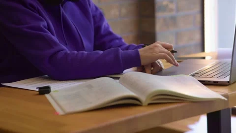 Positioned at table surrounded by study materials and laptop student typing on Video stock 279565879