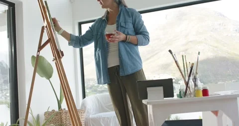 Positioning canvas, painter is dipping brush and brushing green hues to capture 库存影片 344340031